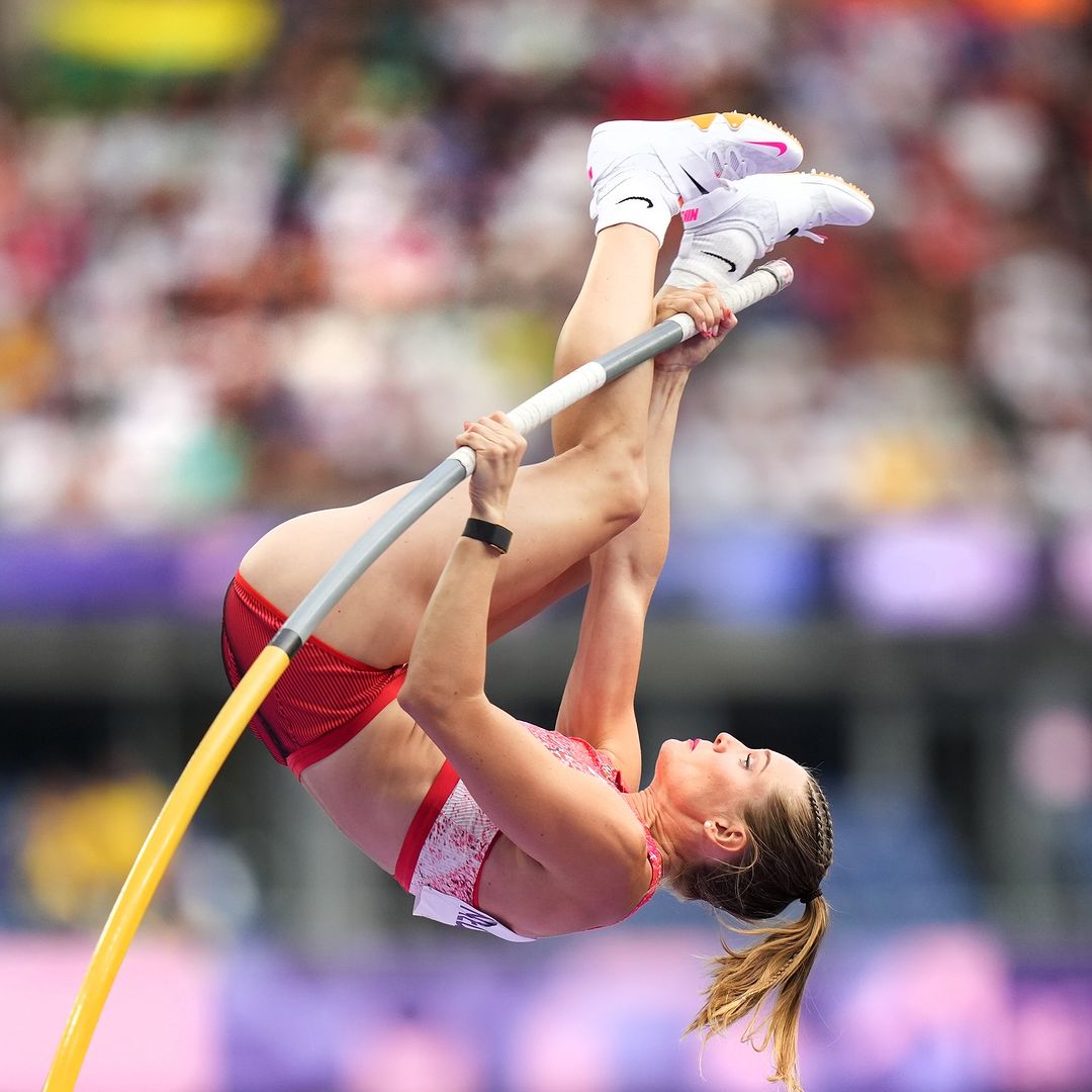 Alysha Newman realizando un salto con pértiga, mostrando la fuerza y destreza que le han llevado a ganar una medalla olímpica.